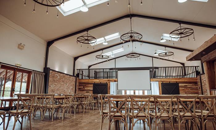 Projector screen surrounded by chairs and tables.